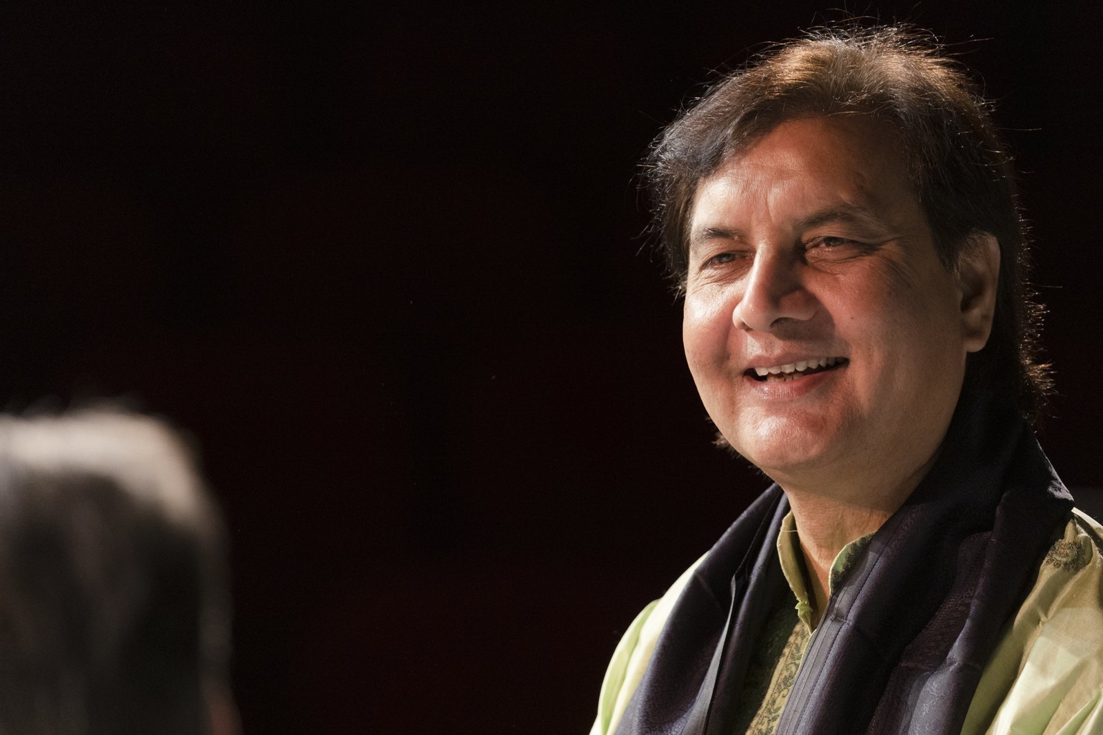 Ustad Akram Khan smiling, in a shawl