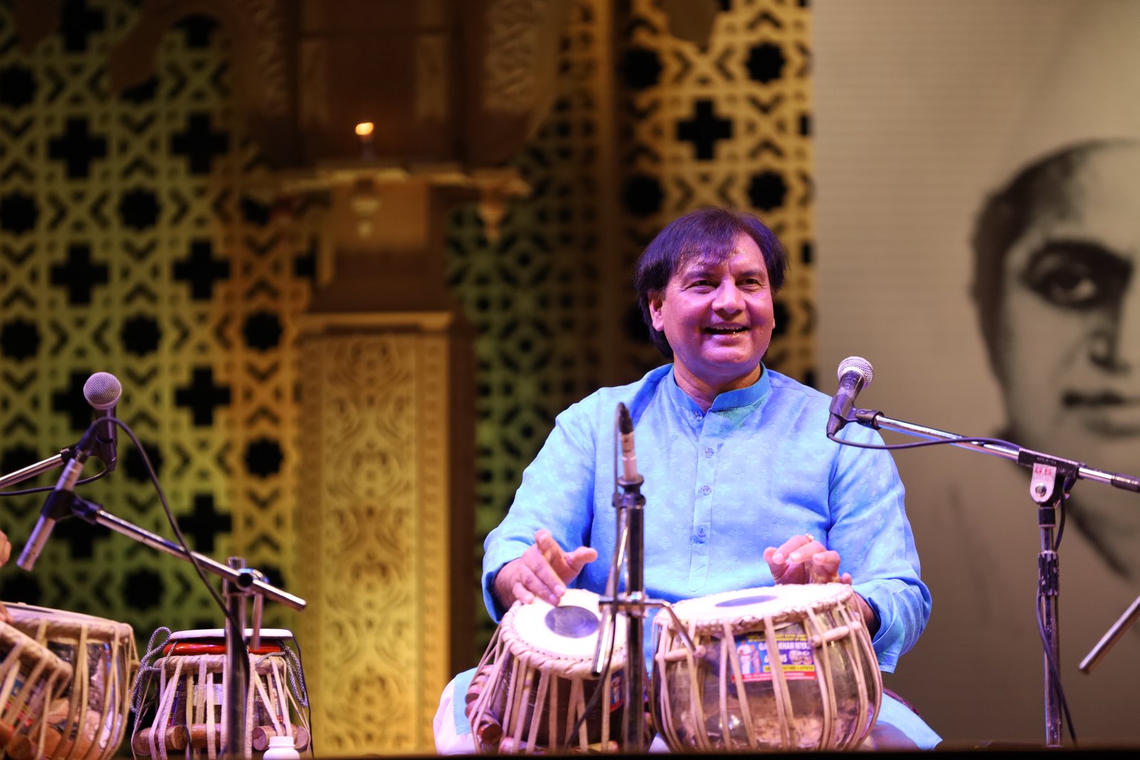 Ustad Akram Khan playing tabla on a decorated stage