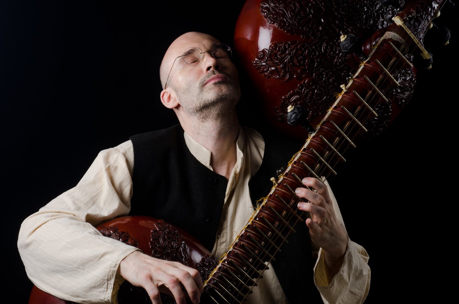 Carsten Wicke with eyes closed, the rudra veena resting on his shoulder