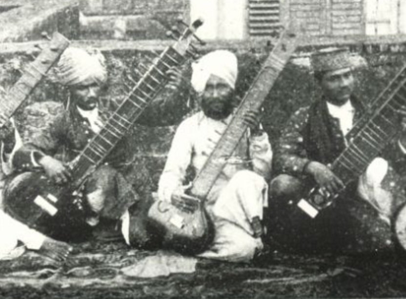 Three seated musicians with sitars, photographed outdoors