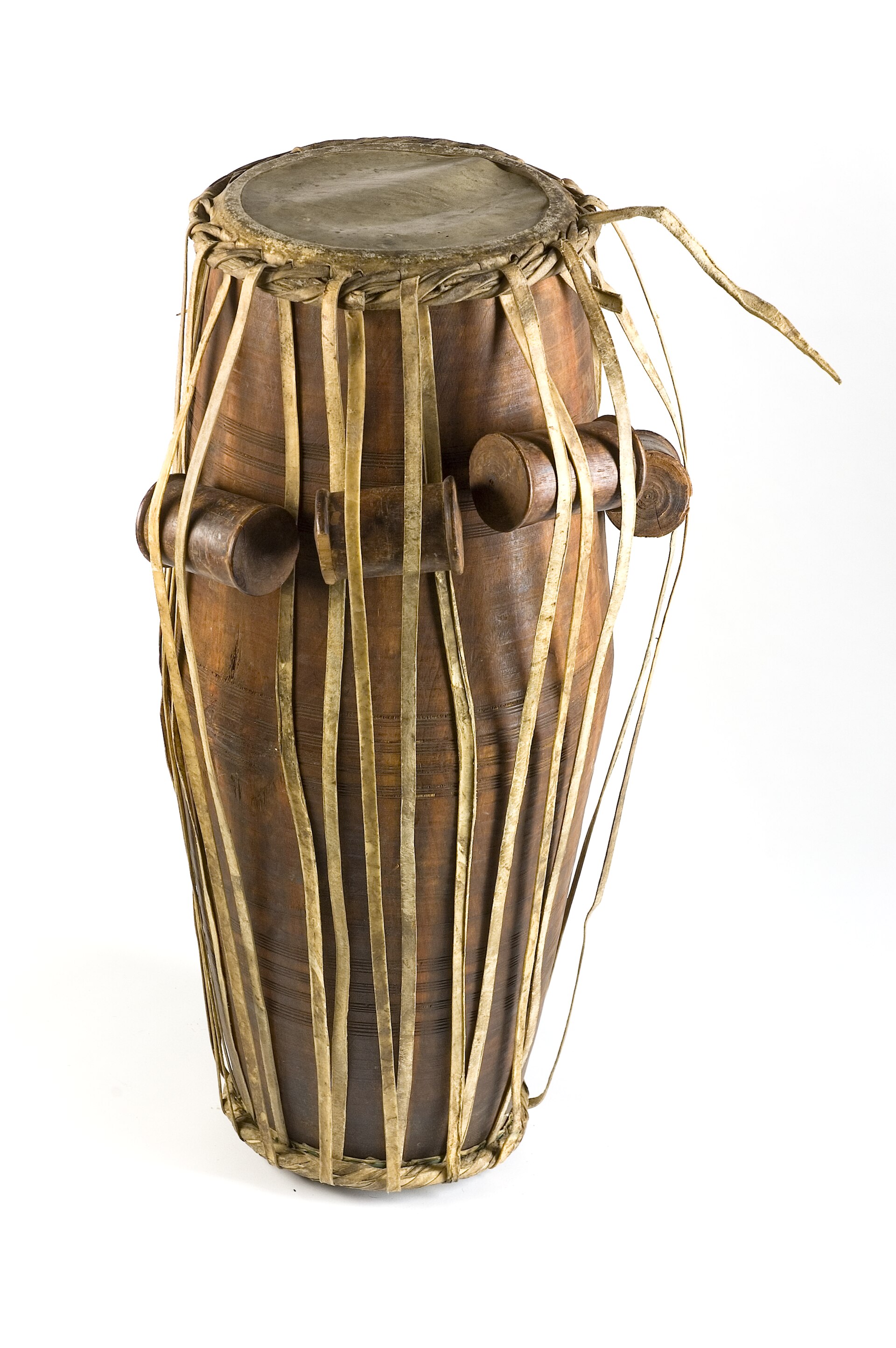A pakhawaj barrel drum standing upright, both heads and the lacing visible.