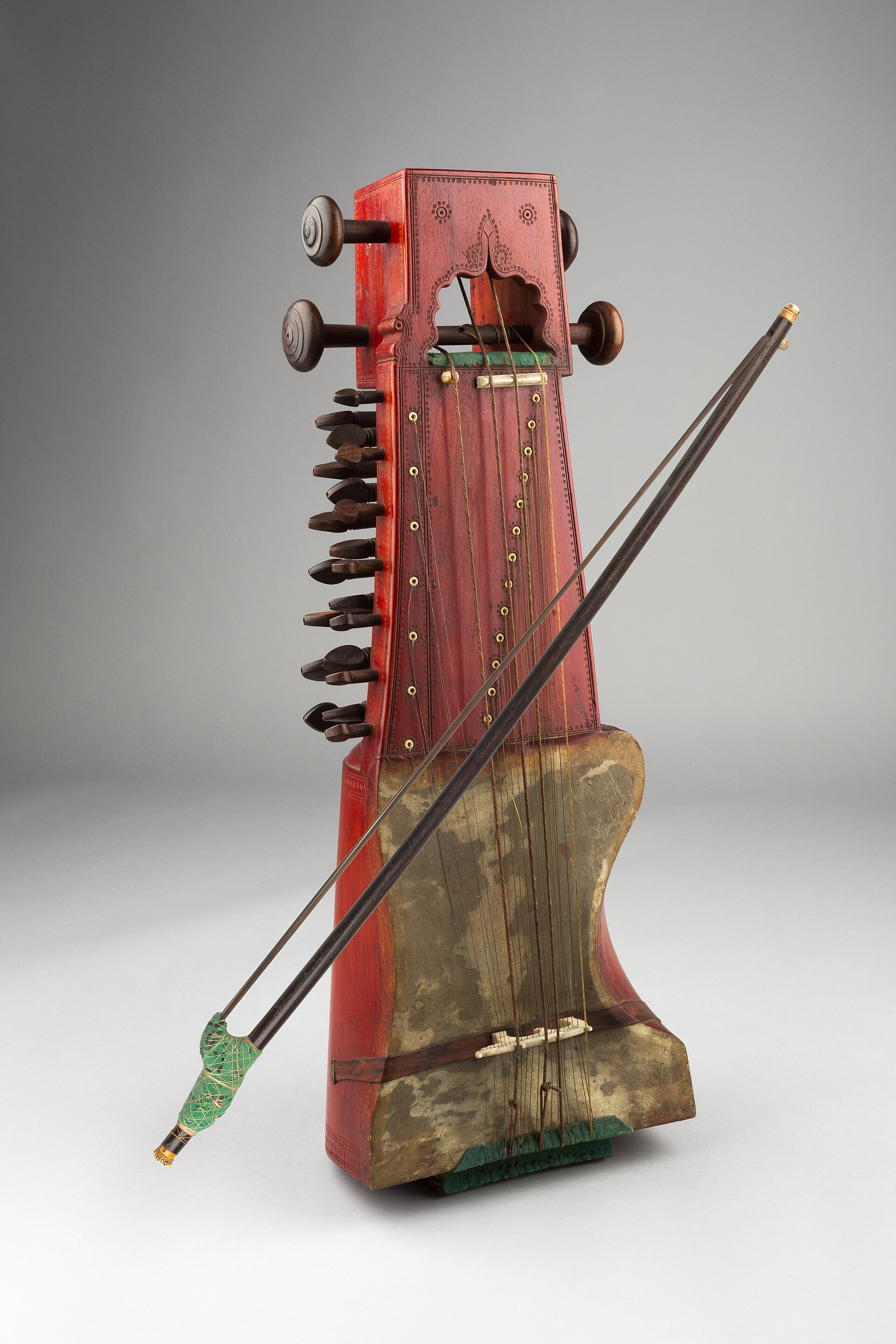 A sarangi standing upright with its bow resting against it.