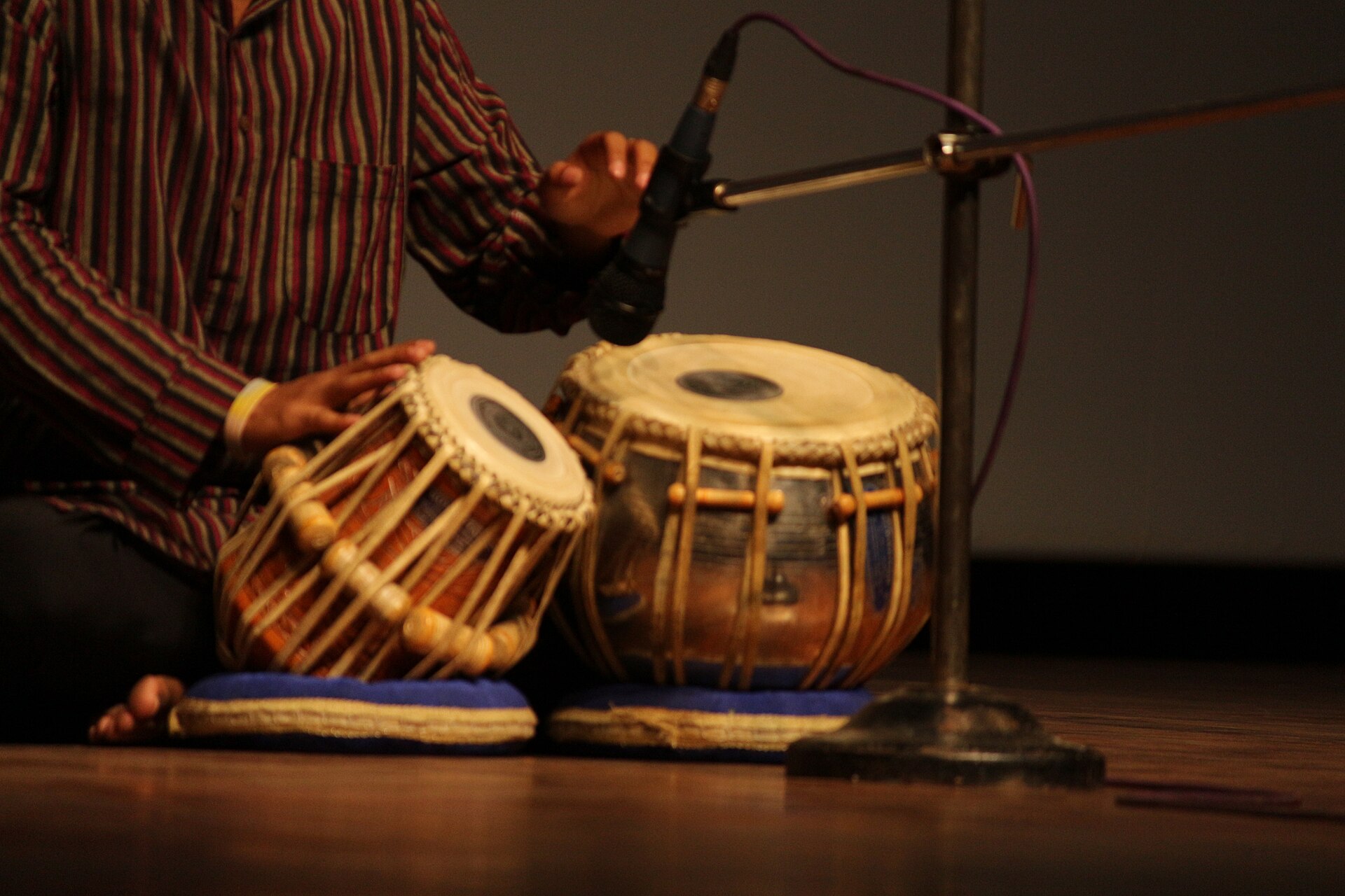 A pair of tabla drums on stage with a player's hands above them.