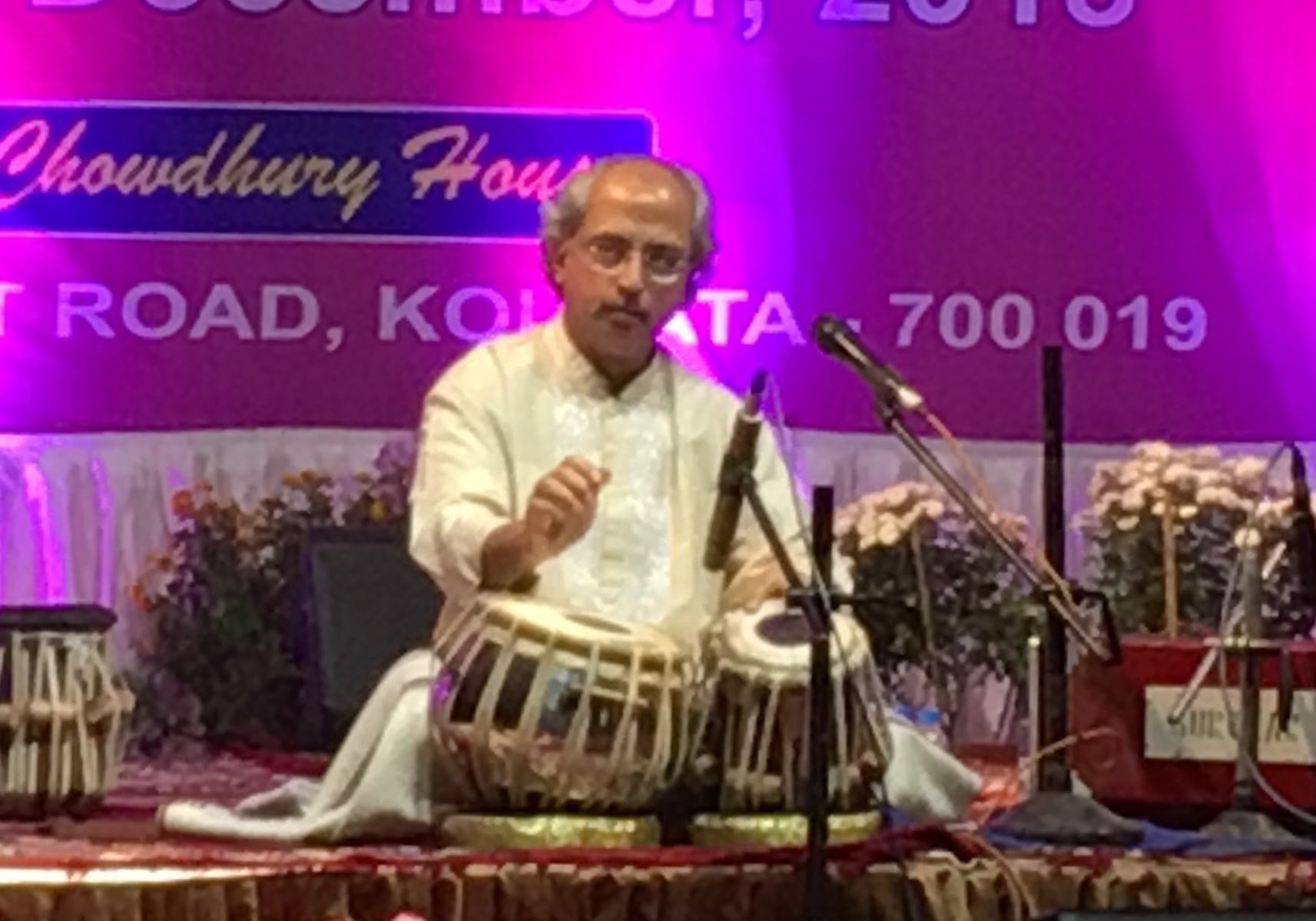 Tabla player Yogesh Samsi seated on stage playing tabla during a concert.